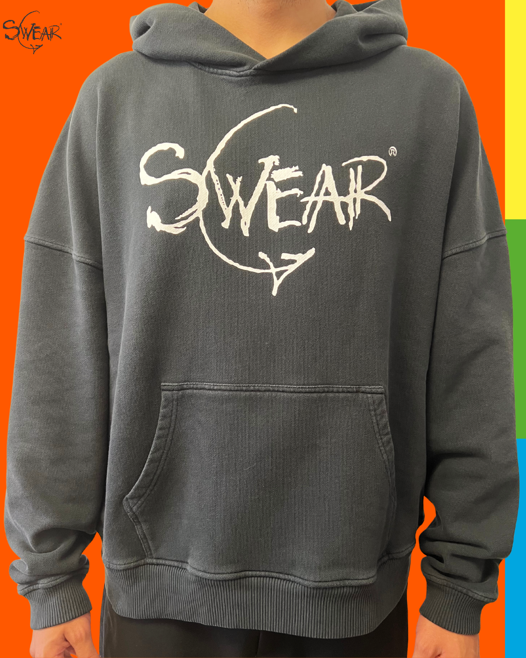 A person wearing a dark gray hooded sweatshirt with a large white 'SWEAR' graphic across the chest, shown against a bright orange background with vertical rainbow color bars on the right side.