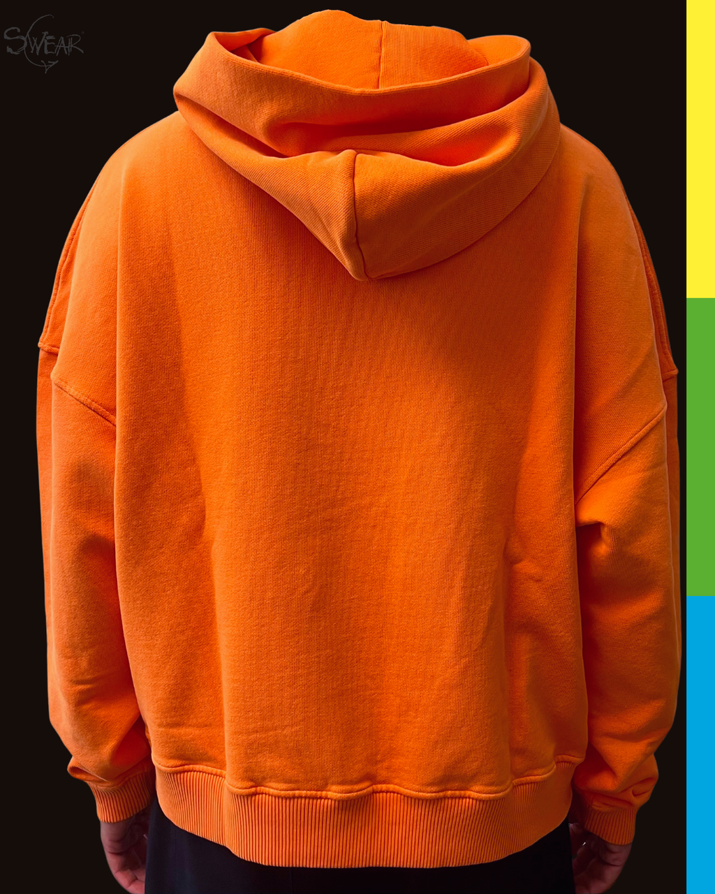 A bright orange pullover hoodie shown from the back, worn by a person against a dark background with a vertical multicolor stripe on the right side.