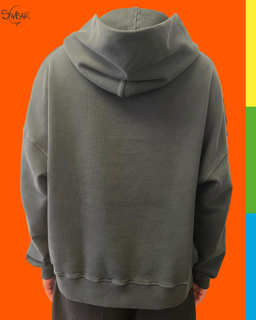 A person shown from the back wearing an oversized ribbed hoodie in a muted gray-green tone, against a bright orange background with a narrow multicolor vertical stripe on the right edge.