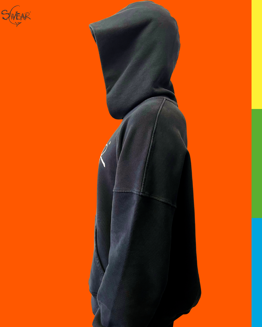 A person wearing a black oversized pullover hoodie shown in side profile against a bright orange background, with a vertical multicolor stripe on the right edge and a small 'SWEAR' logo in the top-left corner.
