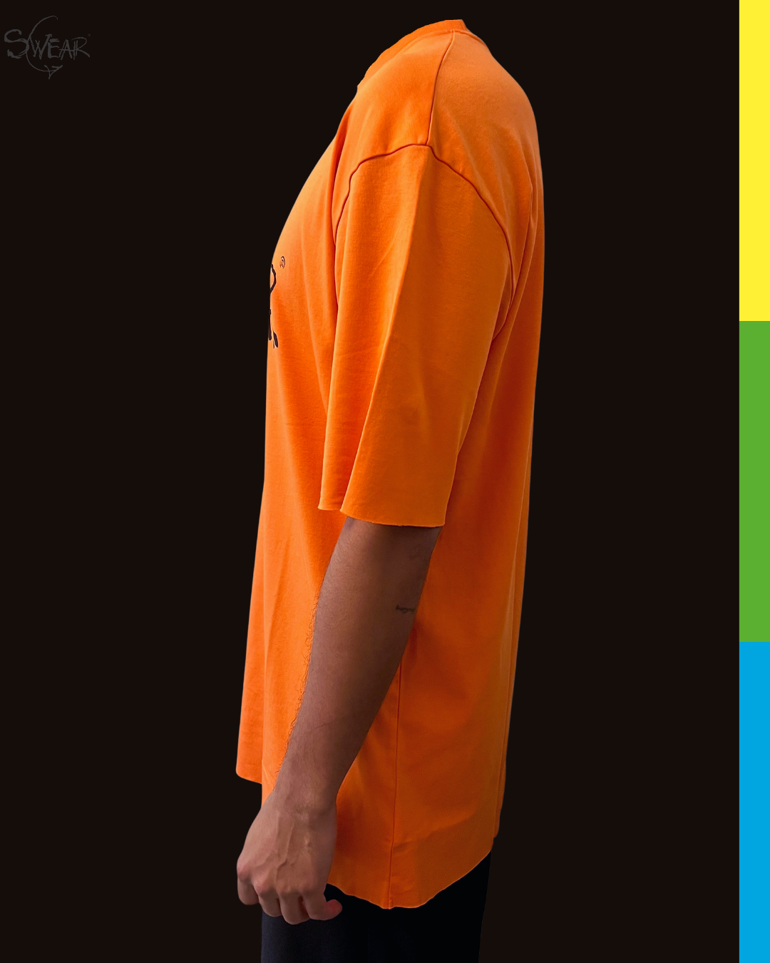 Side profile of a person wearing an oversized bright orange t-shirt against a dark background, with a vertical color calibration strip on the right edge.